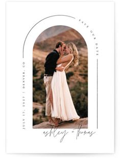 an image of a couple kissing in front of the mountains with their arms around each other