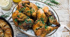 a plate full of cooked chicken next to some bread and other food on a table