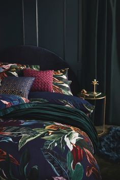 a bed with colorful comforters and pillows in a room that has dark green walls