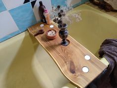 a wooden tray with candles on it sitting in a bathtub next to a towel