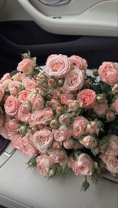 a bunch of pink roses sitting on top of a car dashboard