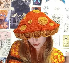 a woman wearing an orange crocheted hat while looking down at her cell phone