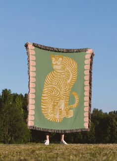 a person standing in front of a green and yellow tapestry with a cat on it