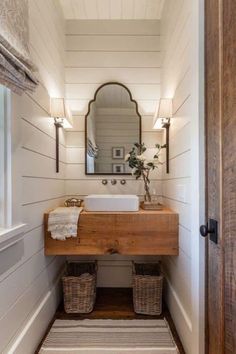 a bathroom with a sink, mirror and two baskets on the floor in front of it