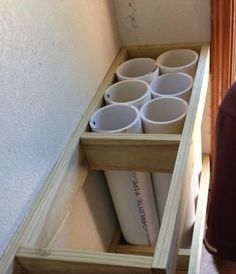 two shelves with cups in them on the floor next to a man's head