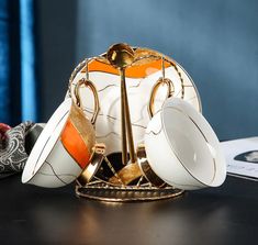 an orange and white tea set sitting on top of a black table next to other items