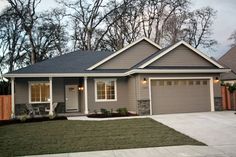 a gray house with two car garages in front of it and trees on the other side