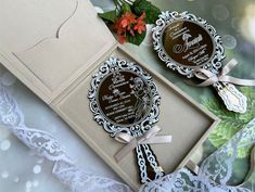 two brown and white wedding cards in a box with ribbon on it, surrounded by flowers