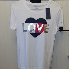 This Is A Great Looking, White T-Shirt With "Love" In Silver With A Background Of A Black White And Red Heart! Very Lightweight, Super Soft And Comfy! Size Xs Combine With Other Items In My Closet To Save On Shipping Or Make Me An Offer! Tommy Hilfiger Graphic Tee With Letter Print, Tommy Hilfiger Graphic Tee With Graphic Print, Tommy Hilfiger Graphic Print Tee, Tommy Hilfiger White Crew Neck Top, Tommy Hilfiger White T-shirt With Graphic Print, Tommy Hilfiger White Graphic Print Top, Tommy Hilfiger White Short Sleeve Top, White Short Sleeve Tommy Hilfiger Top, Tommy Hilfiger Graphic Tee