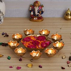 there are many small bowls with flowers on the table next to each other and one has a candle in it