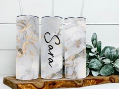 three marble candles with the word cara written on them next to a succulent plant