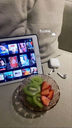 a bowl of fruit sitting on top of a table next to an ipad