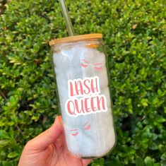 a person holding up a glass with the words flash queen on it in front of some bushes