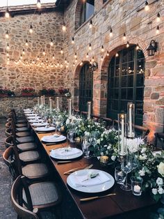 a long table is set with place settings and flowers on it for an elegant dinner