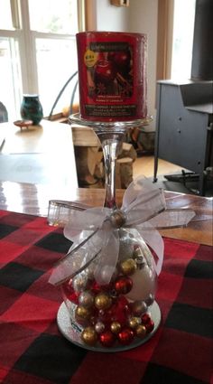 a wine glass filled with ornaments on top of a red and black checkered table cloth