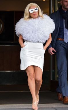 lady in white dress walking down the street with sunglasses on her face and man wearing suit