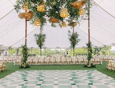 a large tent with tables and chairs set up for a wedding reception in front of a checkered floor