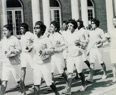 black and white photograph of women running in front of a building with columns on the side