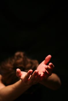 a woman holding her hands up in the air with one hand extended out to catch something