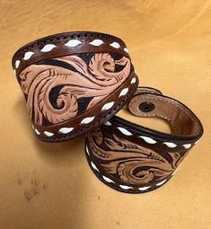 two brown and white leather wristbands sitting on top of a table