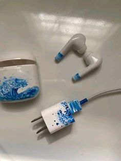 two ear buds sitting on top of a sink next to an ipod charger and headphones