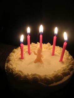 a birthday cake with lit candles in the shape of a teddy bear and five smaller ones