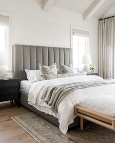 a bed with white linens and pillows in a bedroom next to two lamps on either side of the bed