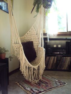 a white hammock hanging from the ceiling in a living room next to a record player