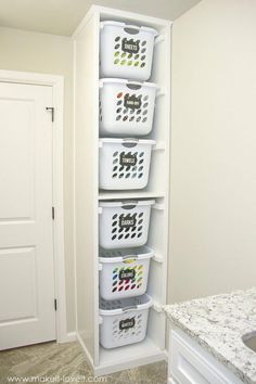 three white baskets are stacked on top of each other in the corner of a room