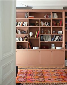 a living room filled with lots of books on top of wooden shelving unit units