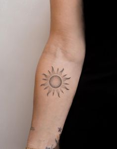 a woman's arm with a sun tattoo on the left side of her arm