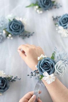 the brides bouquet is being made with blue roses and white flowers on her wrist