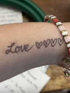 a woman's arm with the word love written in cursive writing on it