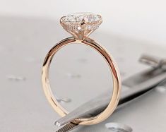 a close up of a diamond ring with a pair of scissors in the foreground