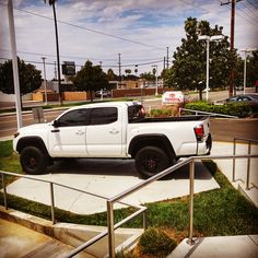 a white truck parked on the side of a road next to a metal hand rail