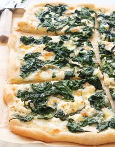 a pizza with spinach and cheese cut into squares