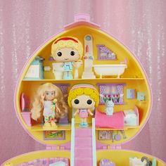 a doll house with two dolls in it and some toys on the shelf next to it