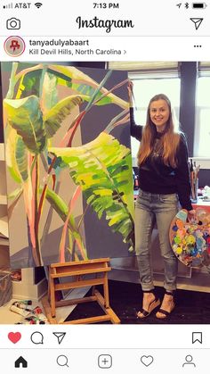 a woman standing in front of a painting holding a paintbrush next to an easel