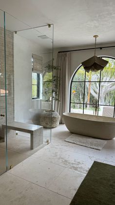 a bathroom with a large bathtub next to a window and a rug on the floor