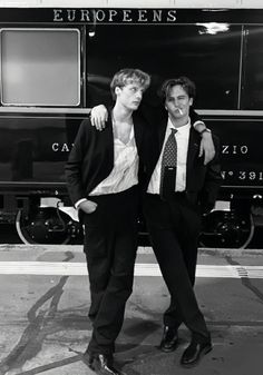 two young men standing next to each other in front of a train car with europeans written on it