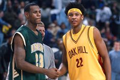 two young men standing next to each other in front of a group of people on a basketball court