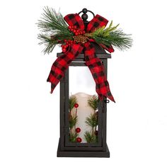 a candle with a red and black bow on it is sitting in a glass lantern