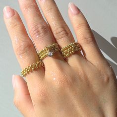 a woman's hand with two gold rings on her left and one in the middle