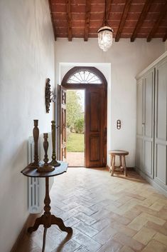 an entry way with a table and two vases on the floor next to it