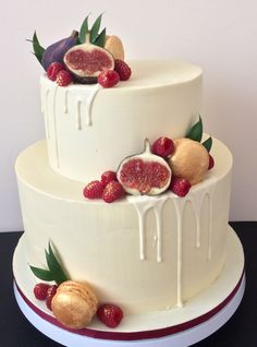 a three tiered cake with figs and berries on the top is decorated in white icing