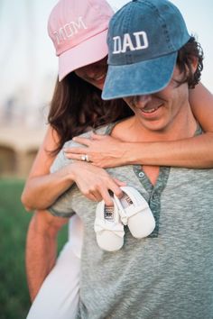 a man and woman hugging each other while wearing baseball caps