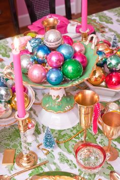 a table topped with plates covered in christmas ornaments and candles next to other decorations on top of a table