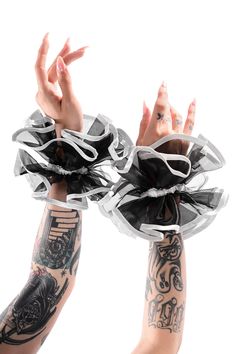 two hands with tattoos holding something in the air