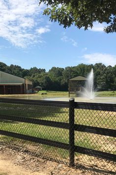 a fire hydrant spewing water into a pond behind a fenced in area