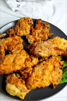 fried chicken and greens on a black plate